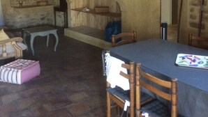 A rustic dining area with a wooden table and chairs, stone walls, and a stone fireplace. - Beautiful stone house in the village of Vers Pont du Gard (Vers-Pont-du-Gard)