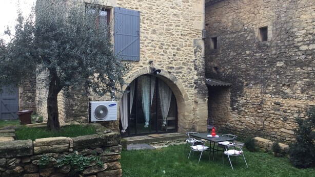 A stone building with a courtyard, a table and chairs, and a tree. - Beautiful stone house in the village of Vers Pont du Gard (Vers-Pont-du-Gard)