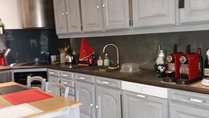 Cucina con mobili grigi, una cappa in acciaio inossidabile, una macchina da caffè rossa e un pavimento decorato.