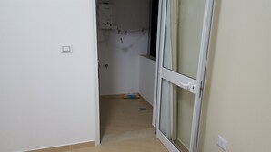 A narrow hallway with a door leading to a room. A broom and a small blue object are visible on the floor. - A charming F1 studio (Sahloul)