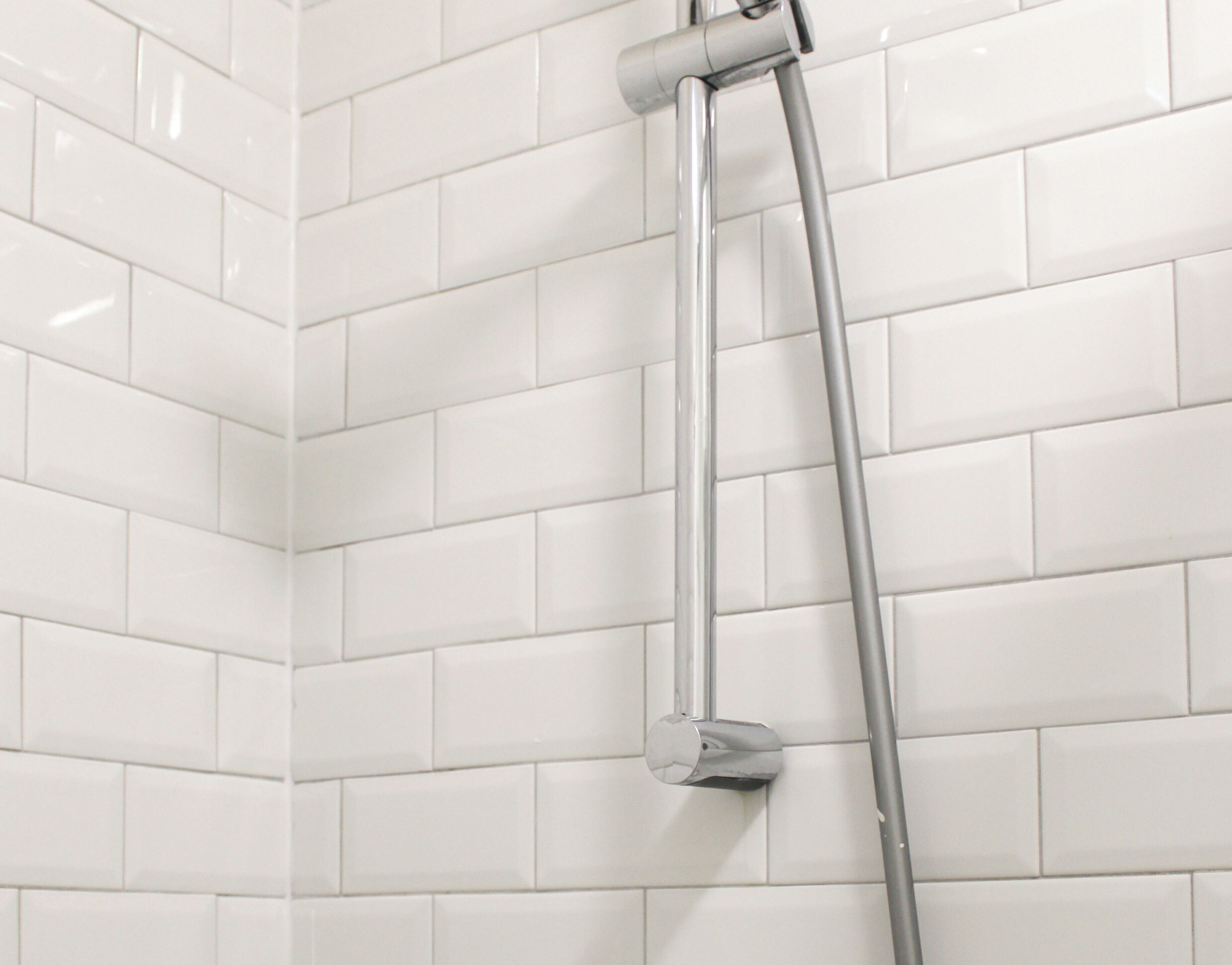Une douche avec un robinet chromé et un long tuyau.