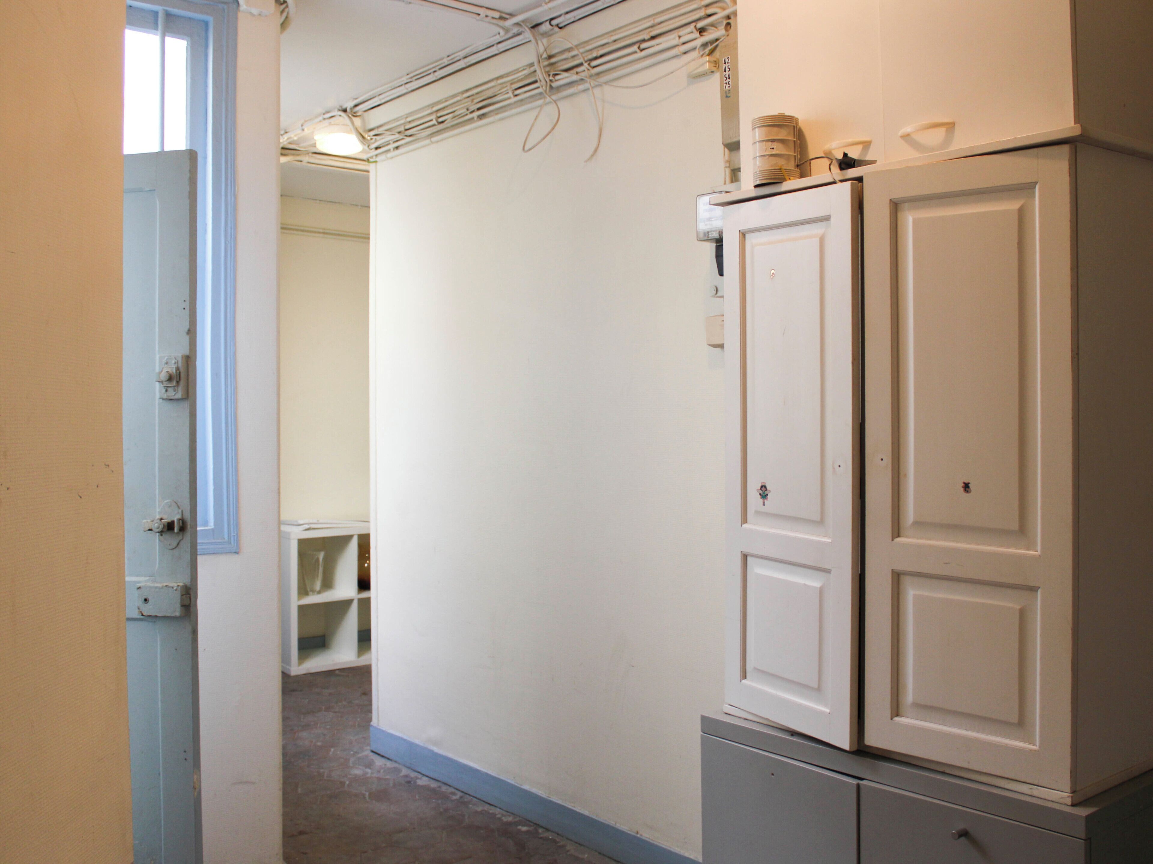 Un couloir avec une porte blanche, un meuble blanc et une étagère blanche.