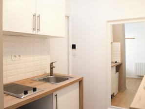 A modern kitchen with white cabinets, a stainless steel sink, and a wooden countertop.