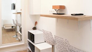 Een moderne kamer met een houten plank waarop een lamp, een afstandsbediening, een magnetron en een stoel met een bijzonder ontwerp staan.
