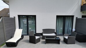 Un patio al aire libre con mobiliario de mimbre, incluyendo un sofá, sillas y una mesa.