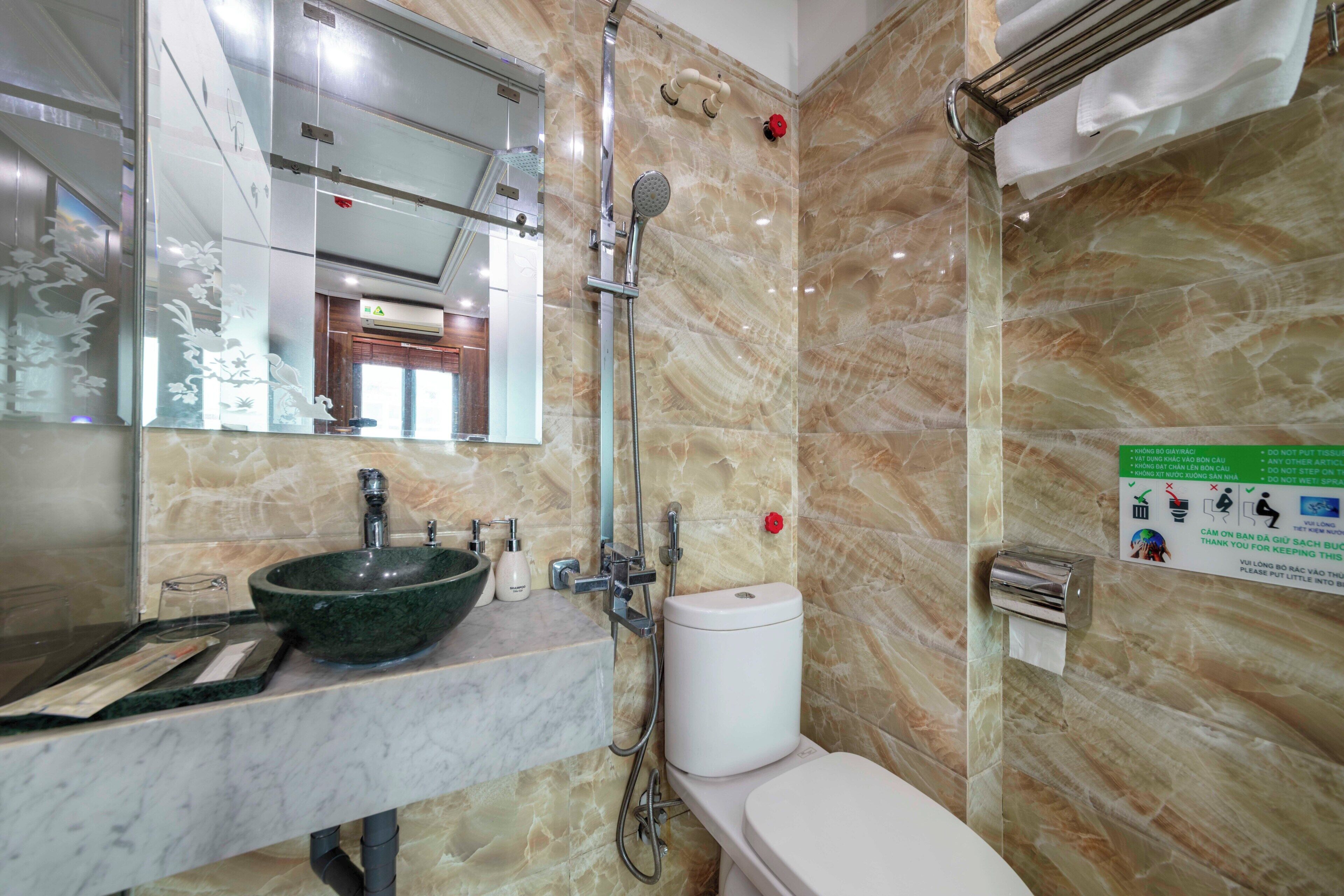 A bathroom with a marble sink, a toilet, and a shower.