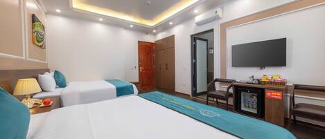 A hotel room with two beds, a desk, a TV, and a minibar.