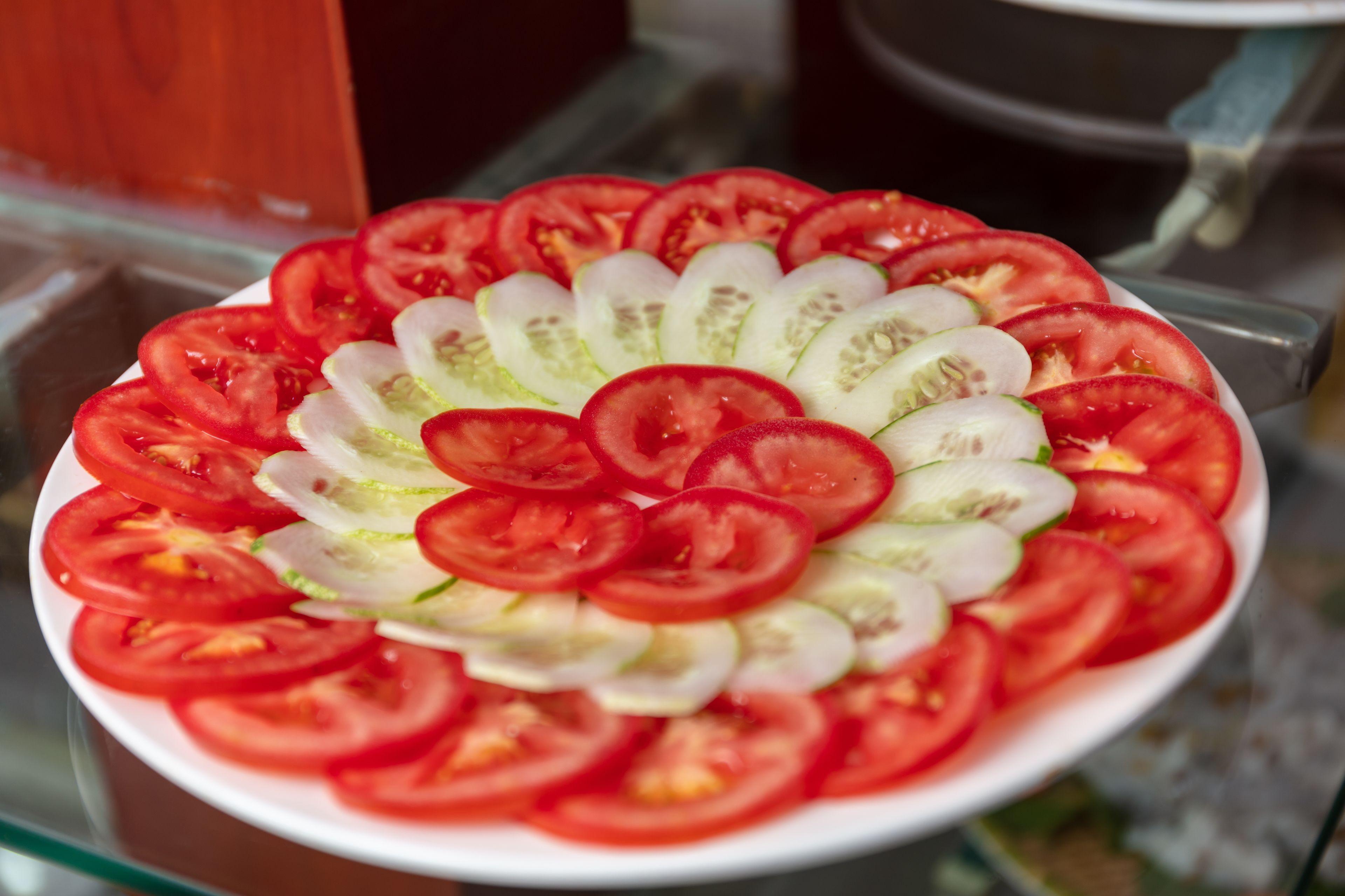 A plate of sliced tomatoes and cucumbers arranged in a circular pattern.
