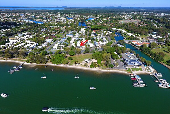 Vista aérea de un pueblo costero con un puerto deportivo, zonas residenciales y una playa.