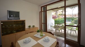 Un coin repas comprenant une table en bois, des chaises, un téléviseur et une vitrine.