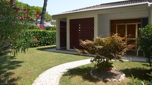 Une maison moderne avec une allée pavée, un petit jardin agrémenté d’un arbre et une clôture en bois.
