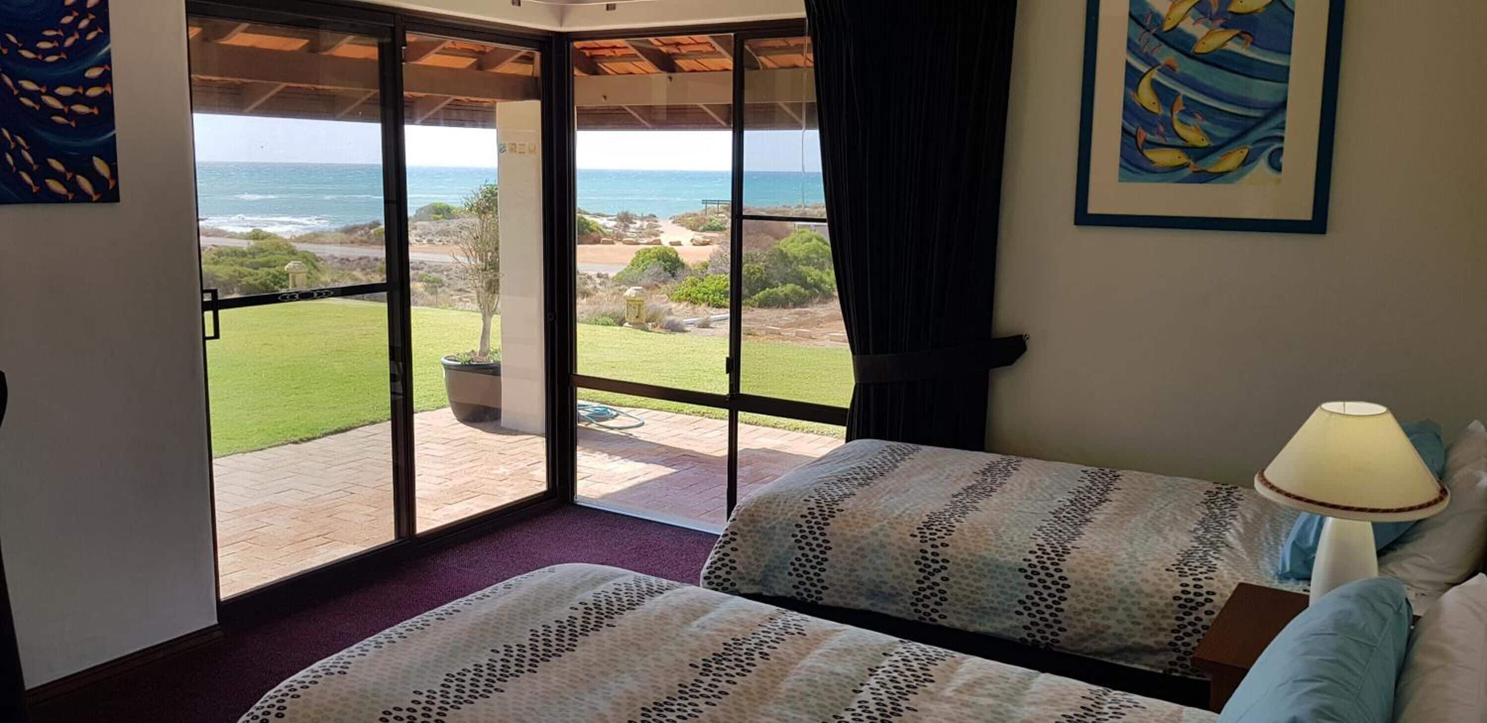 A bedroom with a large sliding glass door leading to a patio with a view of the ocean.