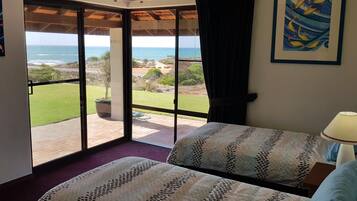A bedroom with a large sliding glass door leading to a patio with a view of the ocean.