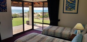 Une chambre dotée d’une grande porte-fenêtre coulissante donnant sur une terrasse avec vue sur l’océan.