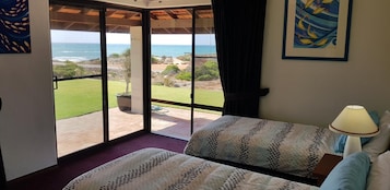 A bedroom with a large sliding glass door leading to a patio with a view of the ocean.