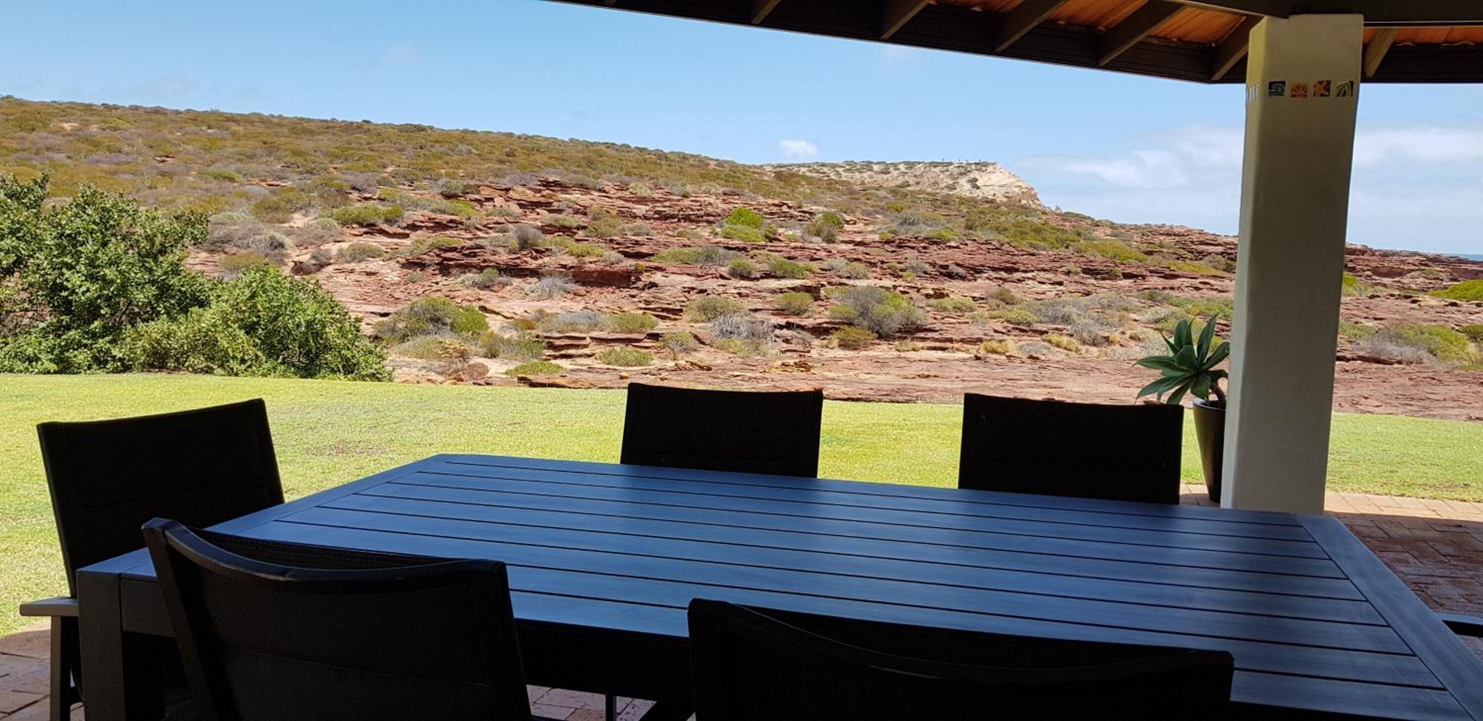 An outdoor patio with a table and chairs, overlooking a rocky landscape with sparse vegetation.