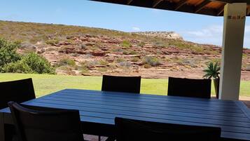 An outdoor patio with a table and chairs, overlooking a rocky landscape with sparse vegetation.
