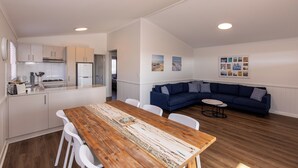 Een moderne keuken met witte kasten, een houten eettafel en een blauwe modulaire bank.