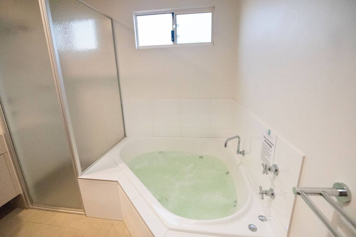 Ein Badezimmer mit begehbarer Dusche, einer Badewanne und einem kleinen Fenster über der Badewanne.