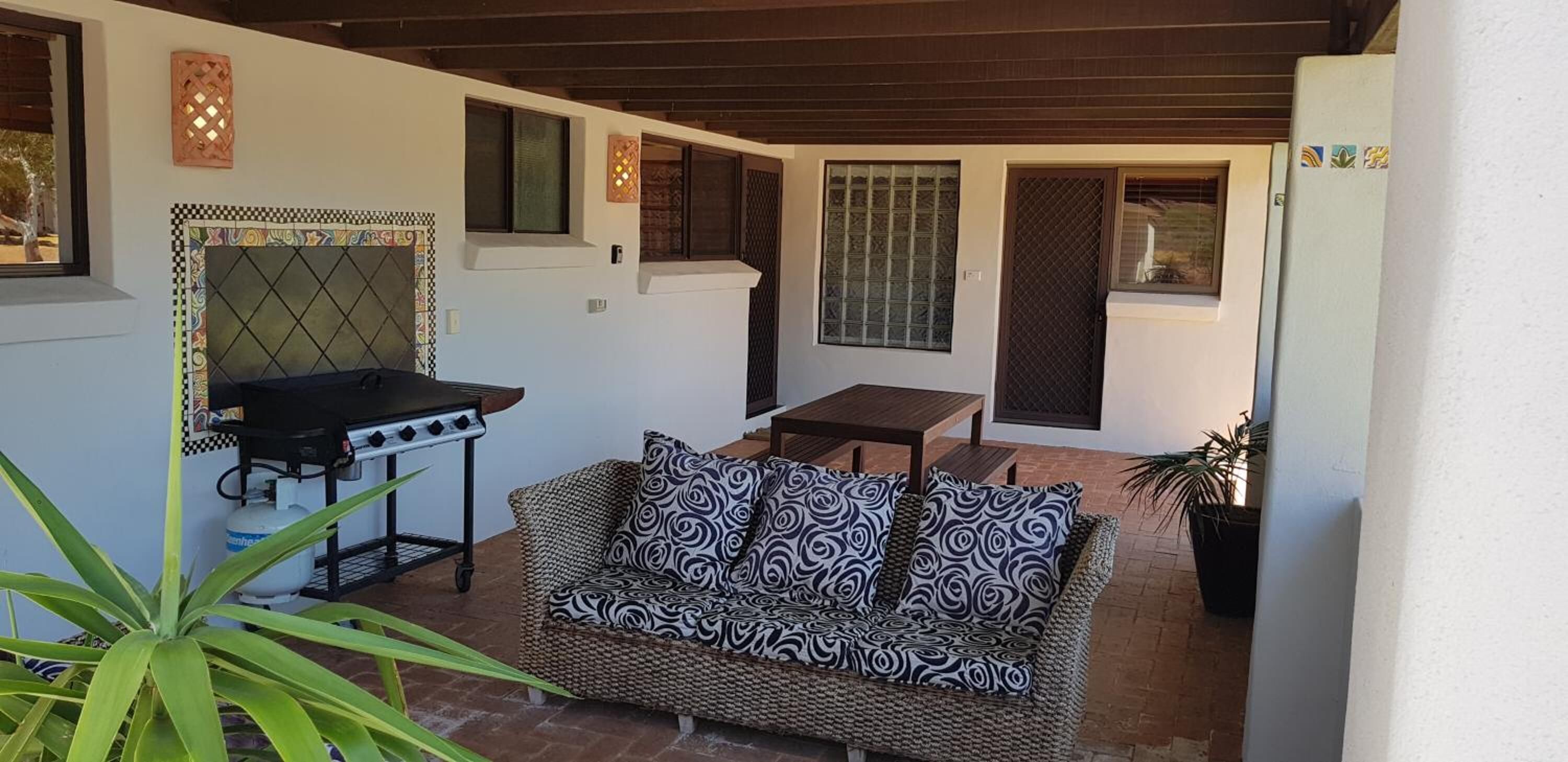 Un espacio al aire libre con patio, una parrilla, un sofá y una mesa.