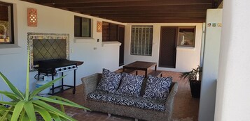 Un espacio al aire libre con patio, una parrilla, un sofá y una mesa.