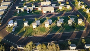 Luchtbeeld van een kustmobielpark met geordende rijen woningen, een centrale weg en een strand op de achtergrond.