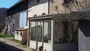 A two-story building with a stone facade and a glass conservatory. - house in farmhouse (saint nectaire)