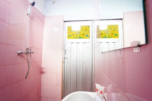 Un baño con baldosas rosas, ducha e inodoro.