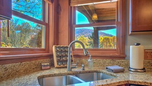 A kitchen with granite countertops, a stainless steel sink, and wooden cabinets.