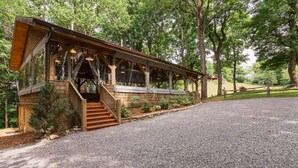 A wooden cabin with a covered porch and a gravel driveway.
