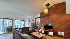 Ein modernes Wohnzimmer mit einem Ecksofa, einem Kamin, einem Fernseher und einem großen Fenster.