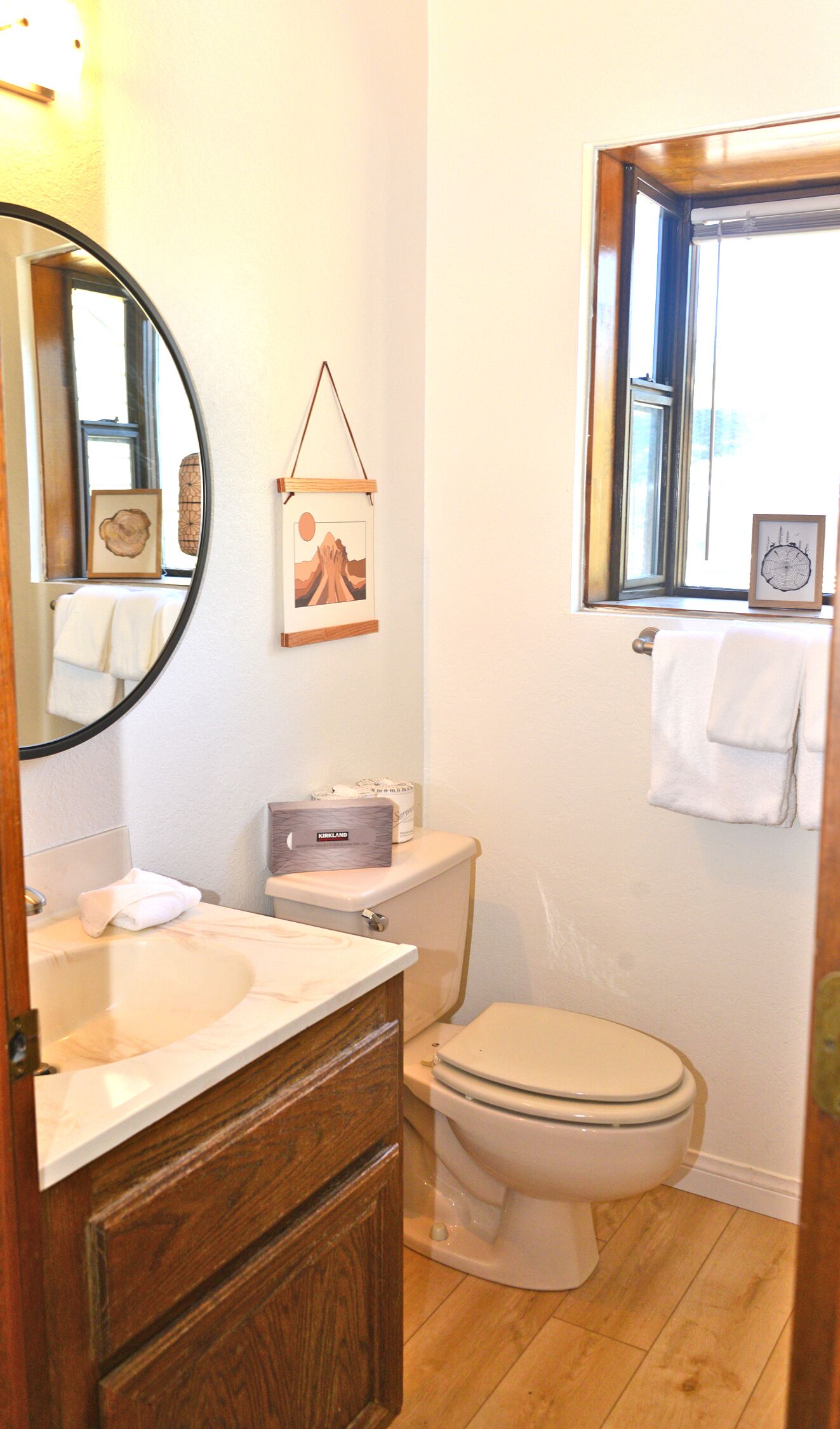 Une salle de bain avec un meuble-lavabo en bois, des toilettes et une fenêtre.