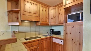 Een keuken met houten kastjes, een spoelbak, een vaatwasser en een magnetron.