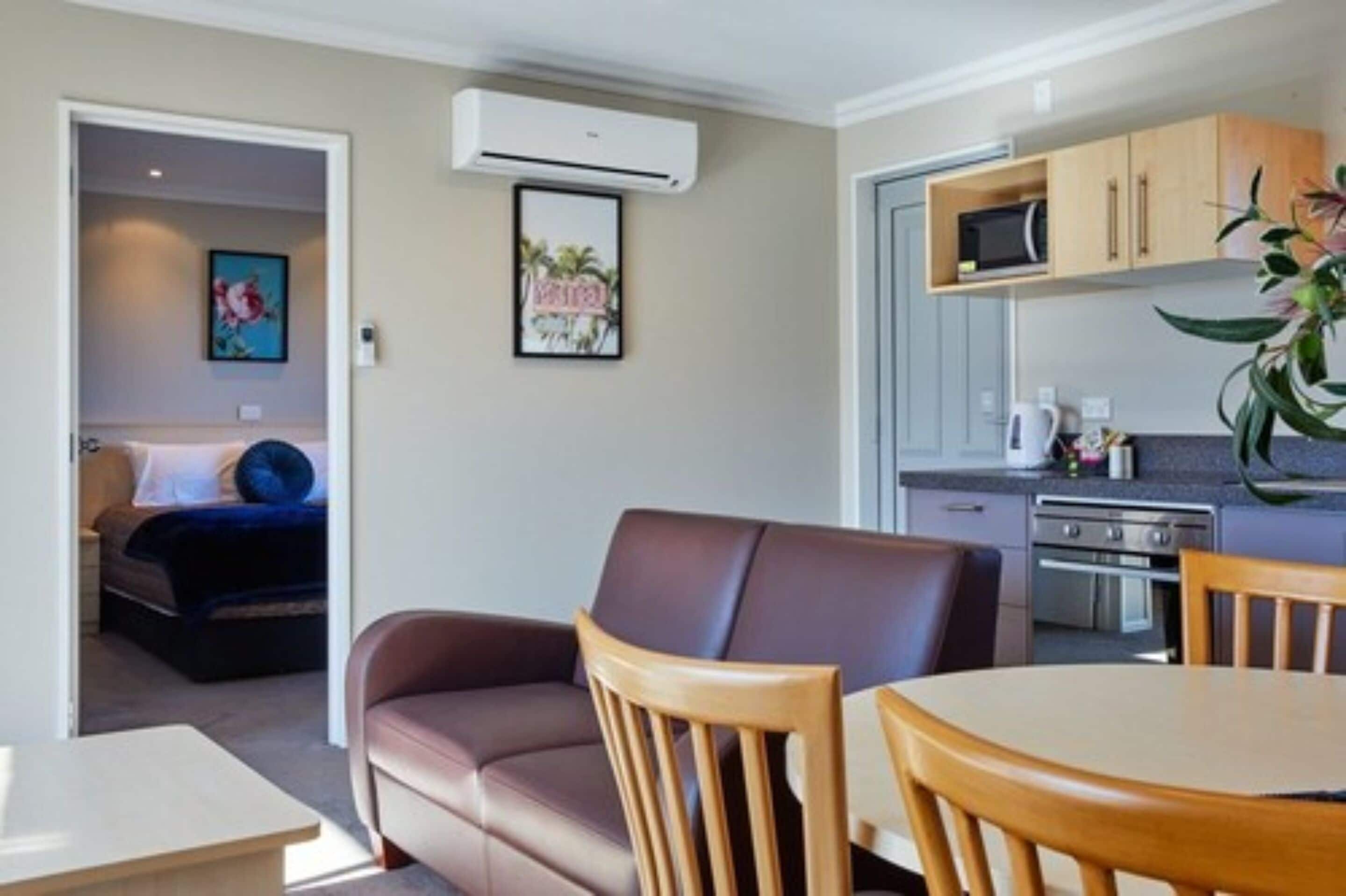 Habitación de hotel pequeña con kitchenette, comedor y dormitorio separado.