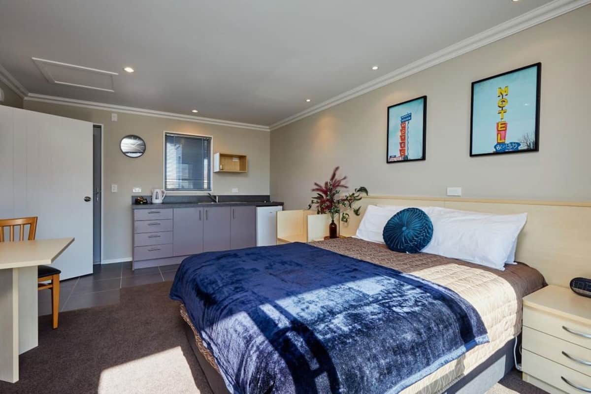 A bedroom with a bed, bedside table, and a desk area.