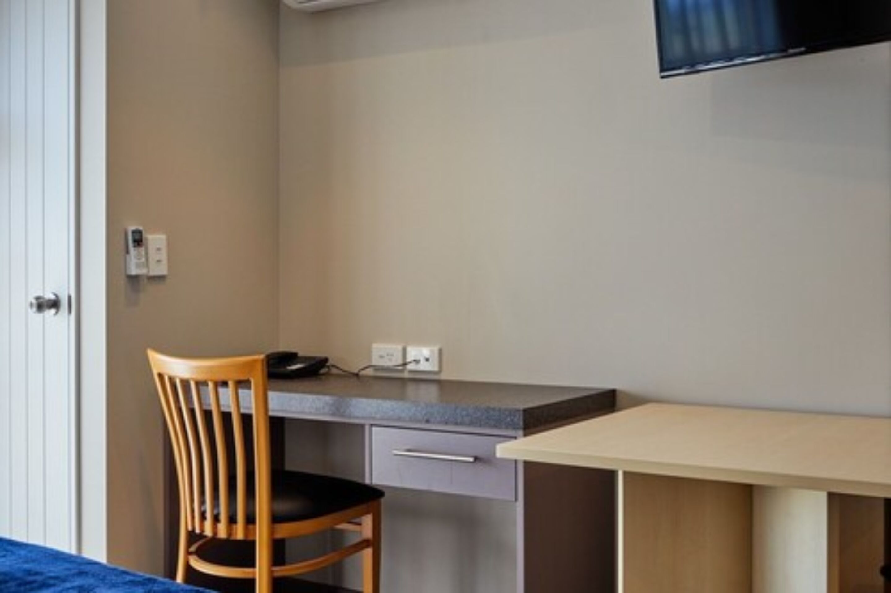 Habitación de hotel con escritorio, silla y televisor de pantalla plana montado en la pared.