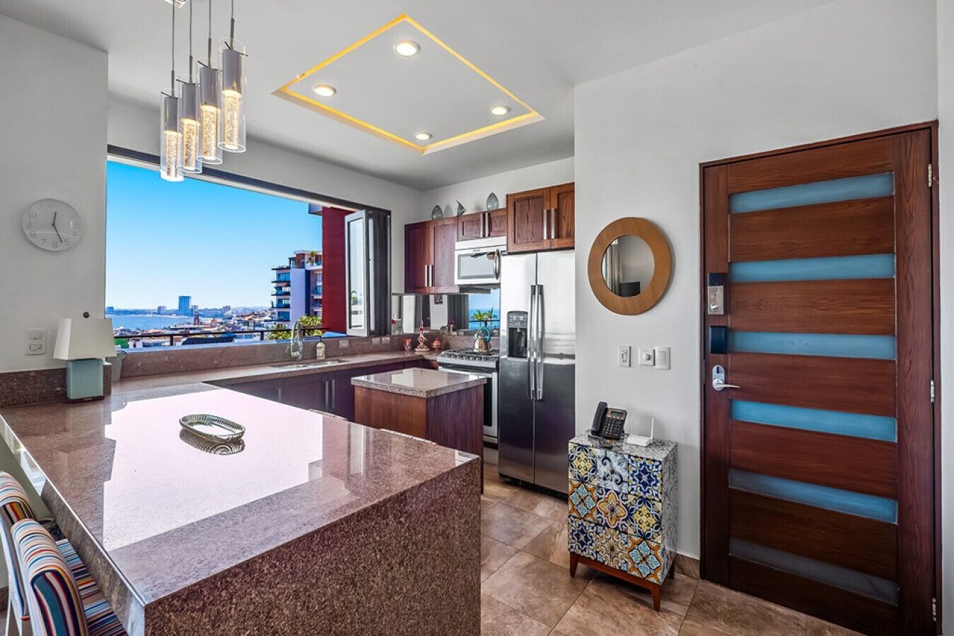 A modern kitchen with a large island, stainless steel appliances, and a view of the city.