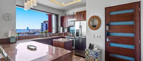 A modern kitchen with a large island, stainless steel appliances, and a view of the city.