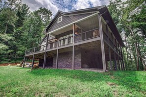 Une maison à deux étages avec un balcon, entourée d’une forêt.
