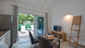 Ein modernes Wohnzimmer mit Schiebetür zu einem Garten, einem Holz-TV-Schrank und einem Regal mit Dekoration.
