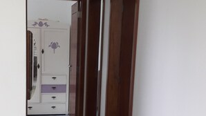 A narrow hallway with patterned floor tiles, wooden doors, and a white wardrobe with purple accents. - 04 - Holiday apartment - Morada Madruga (Praia do Sonho (Ens Brito))