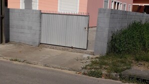 A two-story building with a pink facade, a grey gate, and a balcony. - 04 - Holiday apartment - Morada Madruga (Praia do Sonho (Ens Brito))