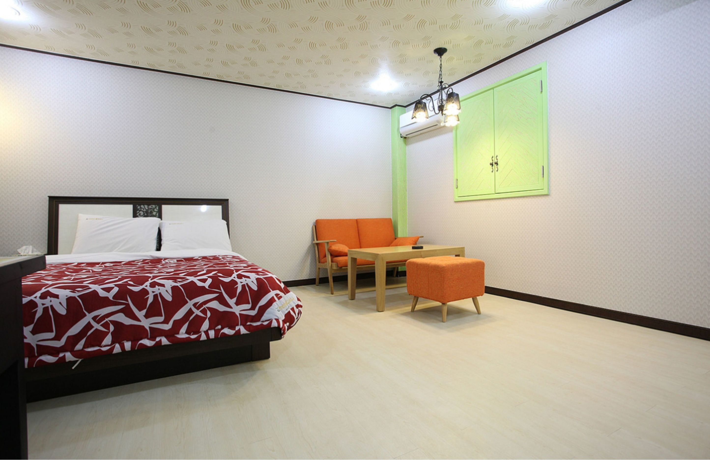 A hotel room with a bed, a small table, two chairs, and a green cabinet.