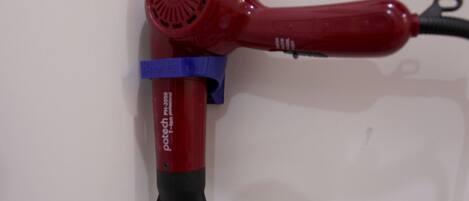 A red hair dryer with a black handle and a blue strap.