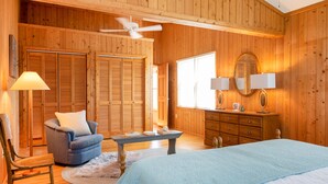 Une chambre à coucher aux murs lambrissés, avec un lit, une chaise, un bureau et une commode.