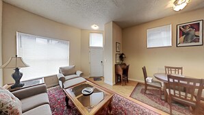 Ein Wohnzimmer mit Sofa, Sessel, Couchtisch und einem Essbereich mit Tisch und Stühlen.