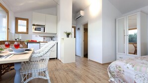 Une cuisine moderne avec des meubles blancs, un four à micro-ondes et un coin repas comprenant des chaises et une table en osier.