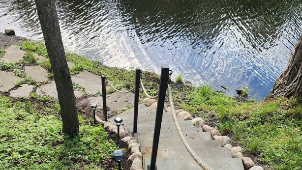 Un sentier qui mène à un plan d’eau, bordé de rochers et de végétation.