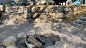 Un foyer en pierre, entouré de rochers, dans lequel brûle une bûche de bois.