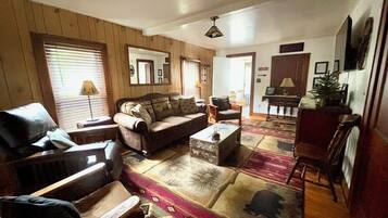 A living room with a sofa, armchairs, a coffee table, and a patterned rug.